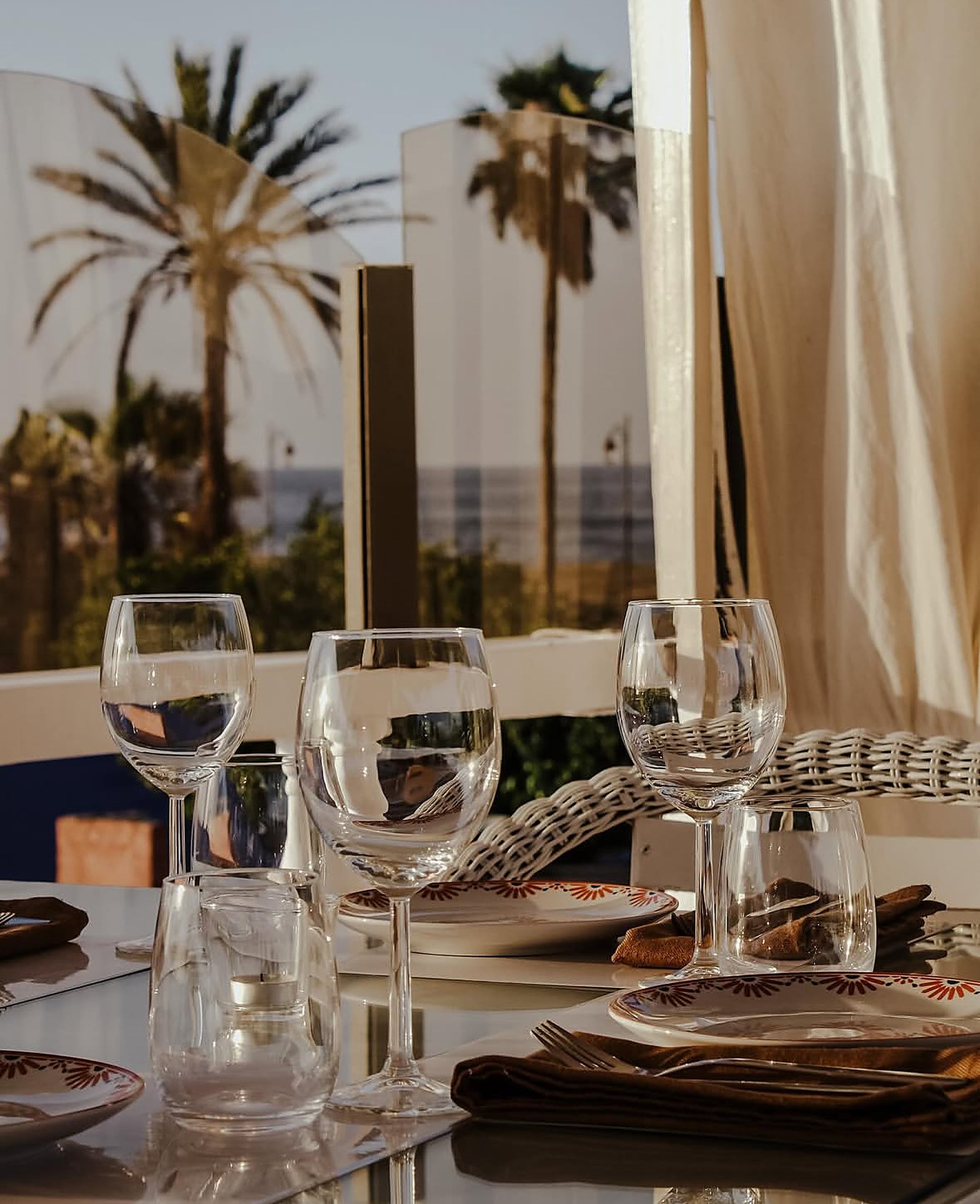 Shooting lifestyle Le 44 Rooftop : table en terrasse au coucher de soleil, palmiers et mer